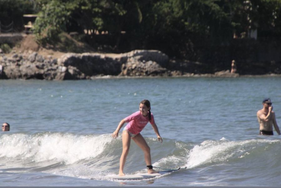 Girl in a pink rash guard riding a wave