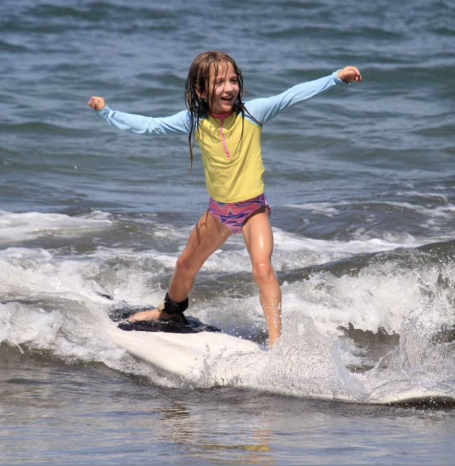 A young girl standing up on a wave